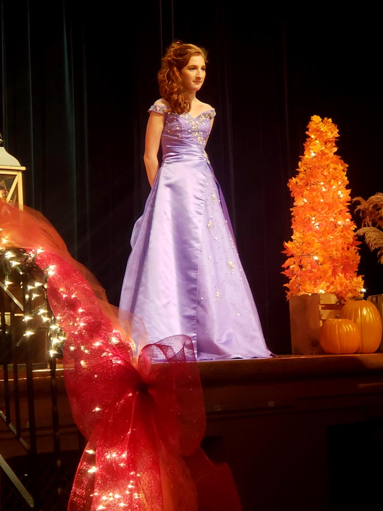 student posing for fashion show in purple dress
