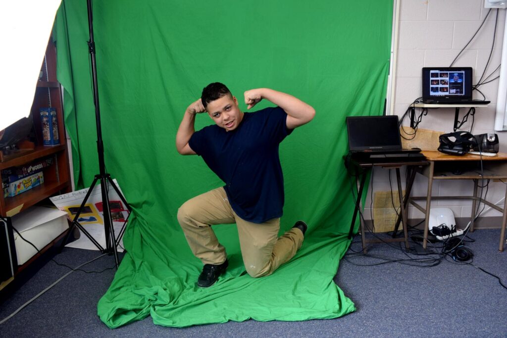 student posing in front of a green screen
