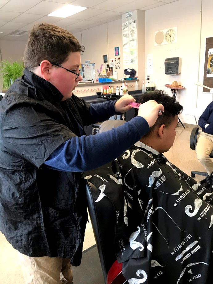 barbering student combing hair